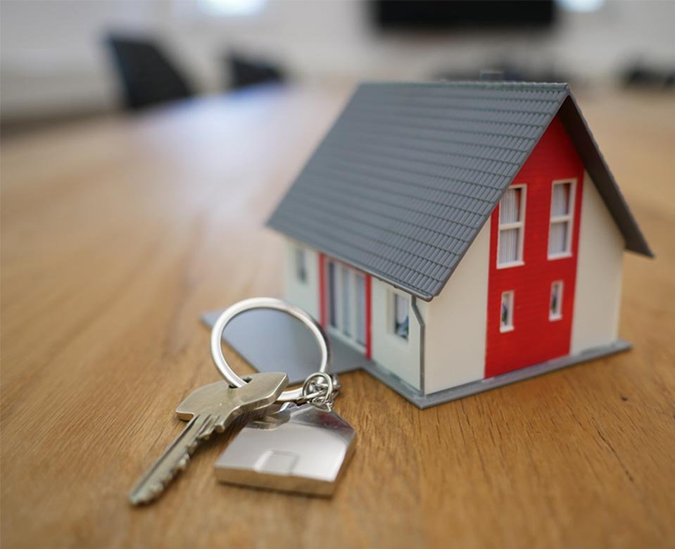 foto de una maqueta sde una casa sobre una mesa de madera y una's llaves al lado-acomapamiento legal hipotecario